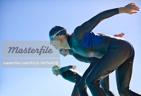 Triathletes diving into water outdoors