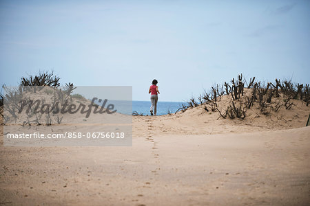 Young Woman Running Through Sand Dunes