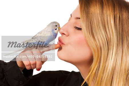Parakeet sitting on womans finger and she gives the bird a little kiss.