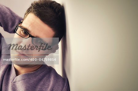 Young man lost in thought against a wall background