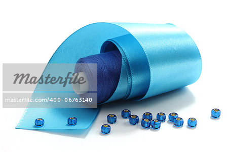 Blue tape, the coil of blue threads and blue  beads on a white background