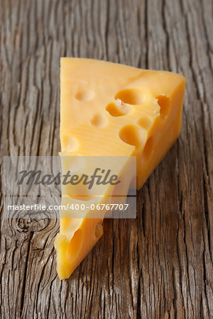 Piece of cheese on an old wooden board.