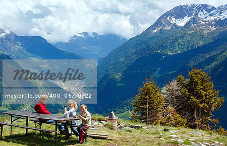 Family (mother with children) rest on summer Alps mountain plateau (Switzerland, Passo del San Gottardo)