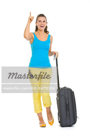Happy young tourist woman with wheel bag pointing on copy space