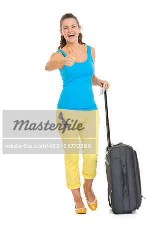 Full length portrait of happy young tourist woman with wheel bag showing thumbs up