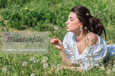 Girl with dandelion lying on green grass