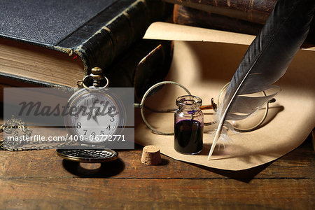 Vintage still life with inkpot and feather near watch and books