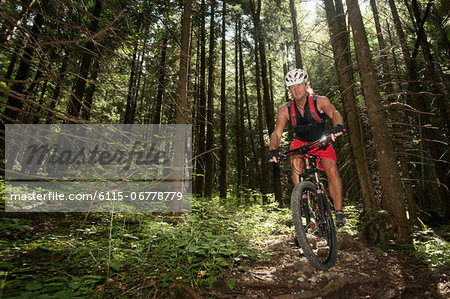 Mountain biker riding downhill in a forest, Wendelstein, Bavaria, Germany