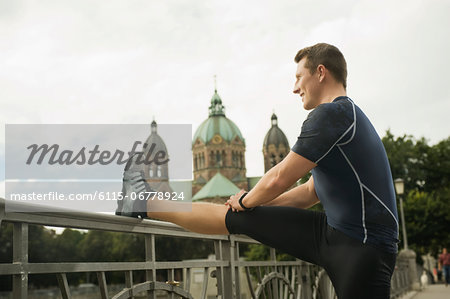Young man stretching on bridge, Munich, Bavaria, Germany