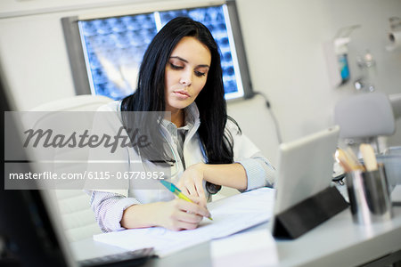Female doctor sitting at desk, doing paperwork, Osijek, Croatia