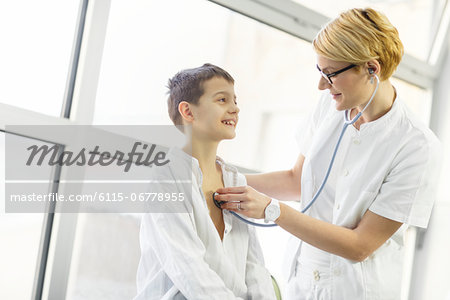 Female doctor using stethoscope on smiling boy, Osijek, Croatia