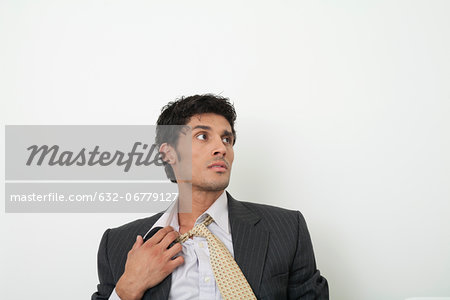 Mid-adult businessman pulling off tie