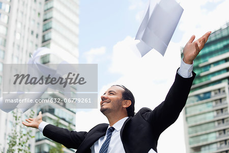 Businessman throwing paper in air, smiling