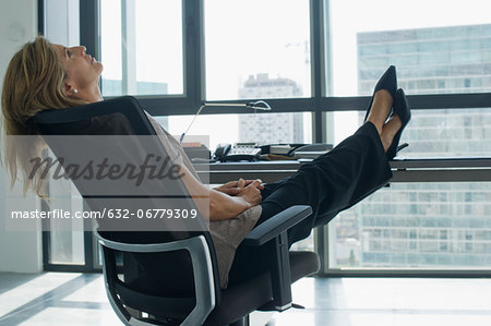 Businesswoman leaning back in chair with feet up on desk