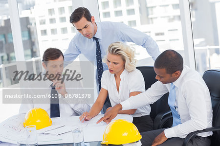 Four architects working on blueprints