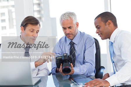 Three business men watching a camera