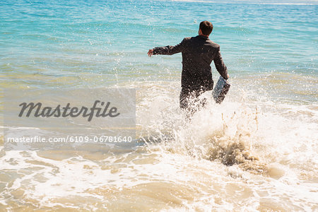 Happy businessman running into the sea