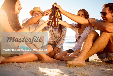 Friends clicking their bottles of beer on the beach