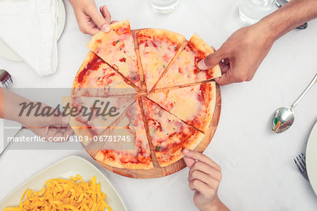 Hands taking slice of pizzas