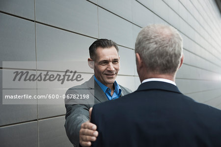 Mature businessmen standing in front of wall, talking