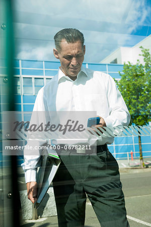 Mature businessman outdoors, looking at smartphone, Mannheim, Germany