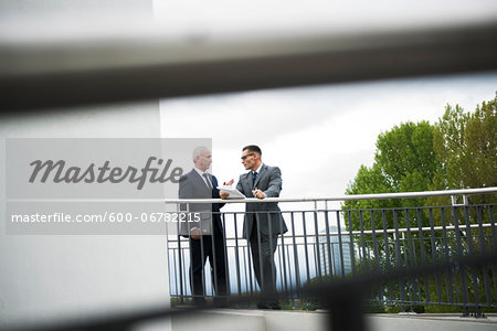 Mature businessmen standing on bridge talking, Mannheim, Germany