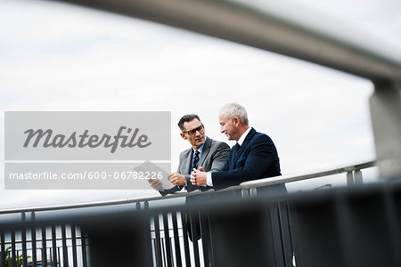 Mature businessmen standing on bridge talking, Mannheim, Germany