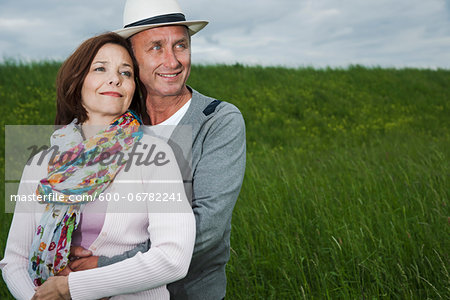 Close-up portrait of mature couple standing in field of grass, embracing, Germany