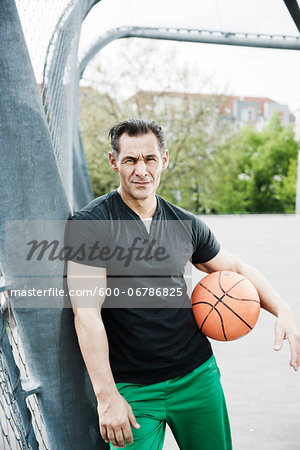 Portrait of mature man standing on outdoor basketball court, Germany