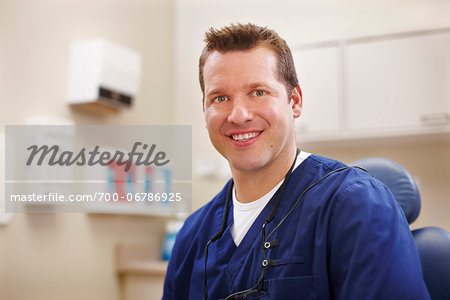 Portrait of male dentist seated in a chair in an examination room.