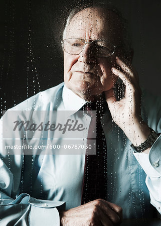 Elderly Man Looking out Window on Rainy Day