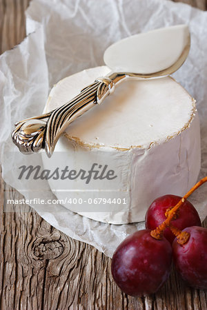 Camembert cheese with knife and grape.