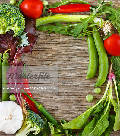 Frame of fresh vegetables and herbs on a wooden background.