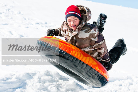 A happy boy up in the air on a tube sleding in the snow.