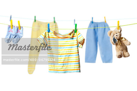 Baby clothes and a tearful teddy bear drying on a rope isolated on white background