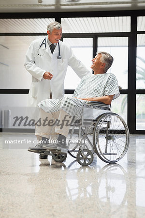 Doctor talking to a man  in a wheelchair smiling  in hospital corridor