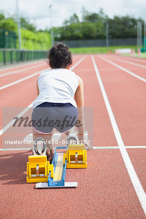 Woman at starting blocks on track field