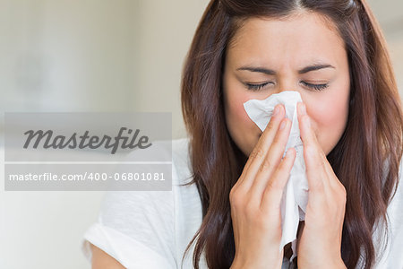 Burnette woman blowing nose into tissue