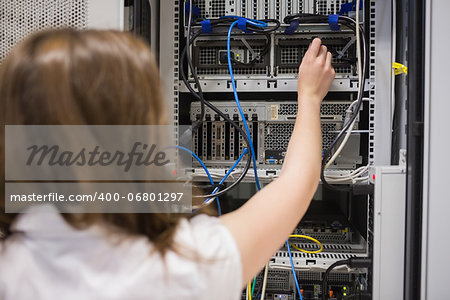 Woman fixing wires of servers in data center