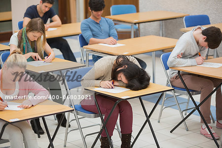 Girl sleeping on desk during exam in exam hall