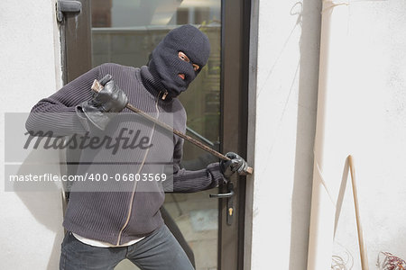 Robber breaking into house through back door using crow bar