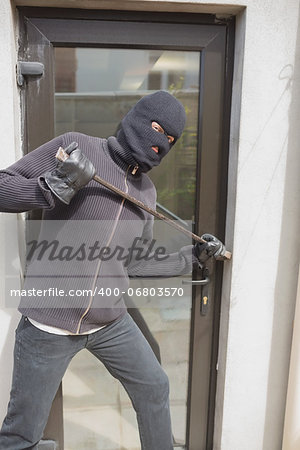 Burglar breaking into home using crow bar through back door