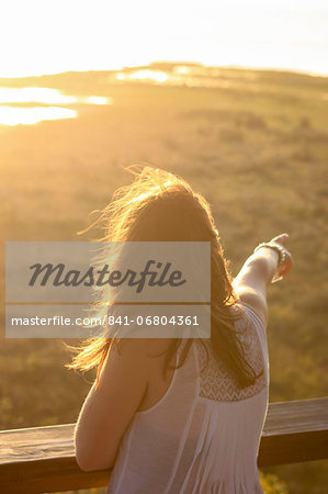 A young woman points out to a water hole at sunset, St. Lucia Wetlands, Kwa-Zulu Natal, South Africa, Africa