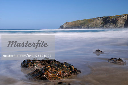 A rising tide swirls around a rock on the beach at Trebarwith Strand, Cornwall, England, United Kingdom, Europe