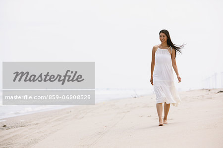 Woman in a white dress walking on the beach