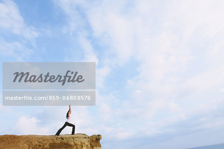 Woman practicing Yoga on a cliff