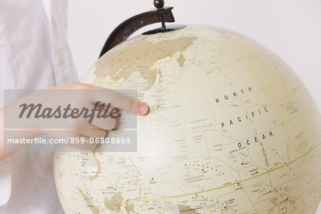 Child pointing a finger on globe