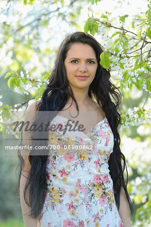 Portrait of a young woman standing beside a flowering cherry tree in spring, Germany