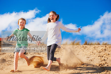 Two girls running down sand dune