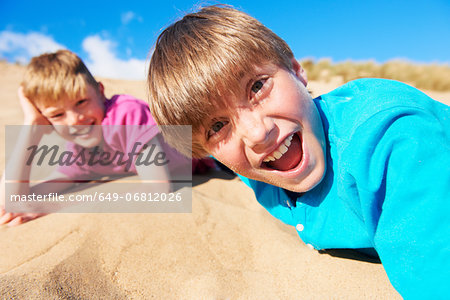 Two blonde haired boys lying on beach